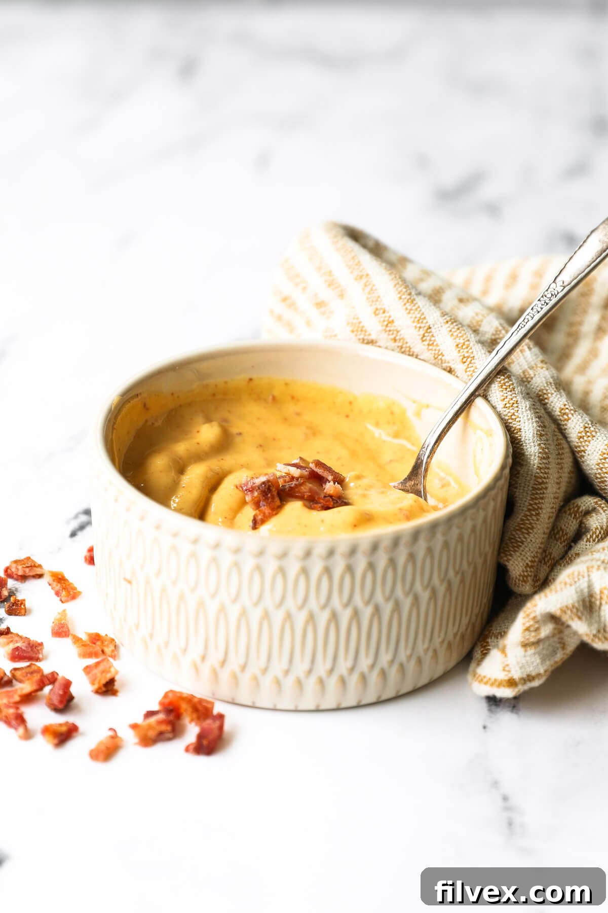 A person pouring oil slowly into a blender to make aioli, illustrating the technique