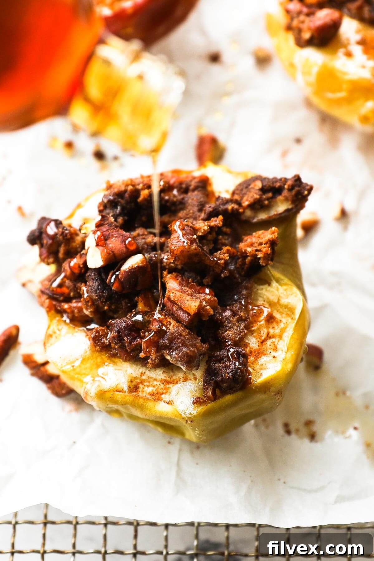 Angled close up image of one air fryer apple stuffed with a crumble topping and drizzling raw honey on top.