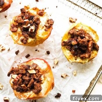 Overhead image of apple halves stuffed with a grain free crumble topping in an air fryer basket with parchment paper.