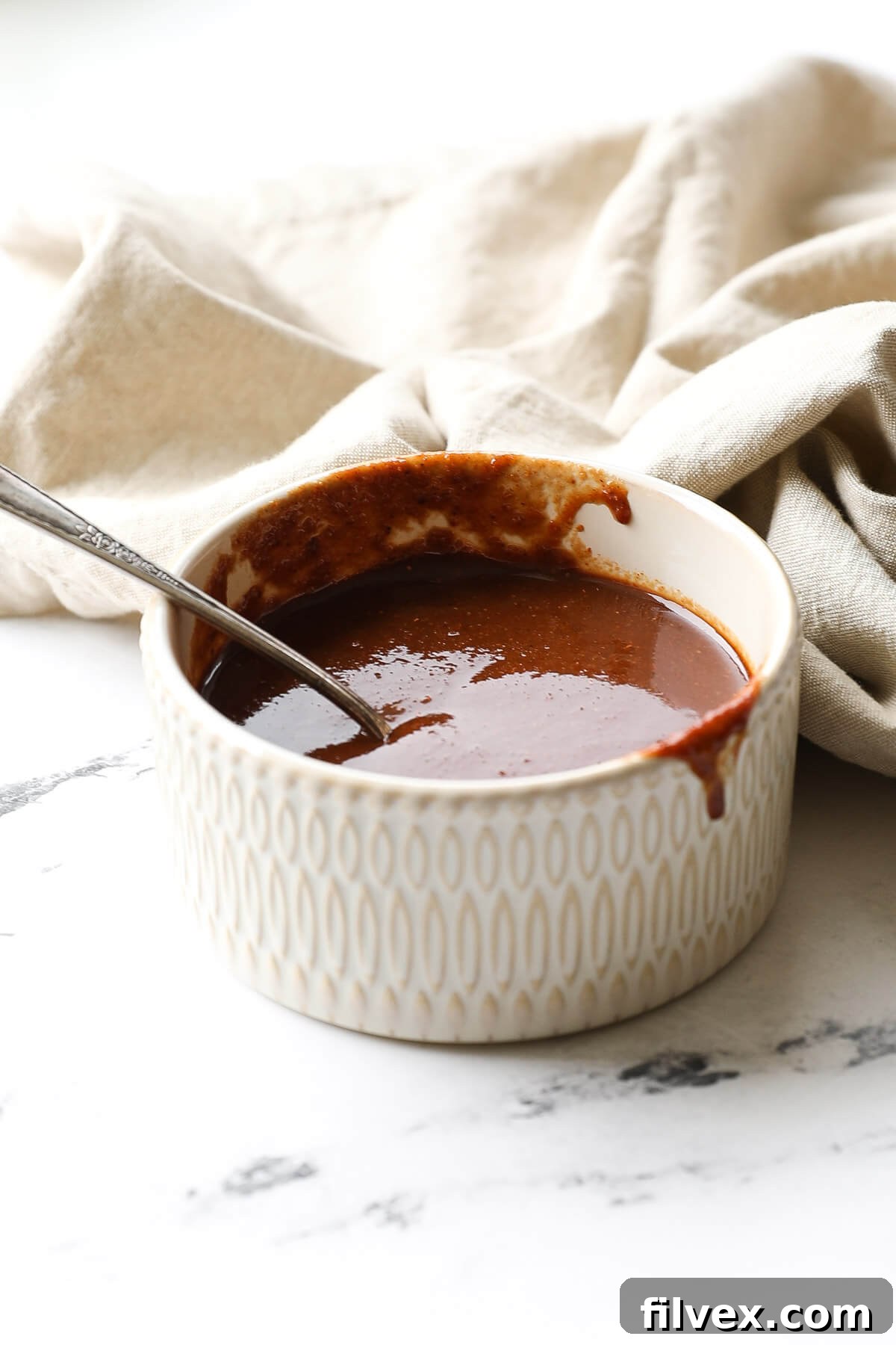 A mixing bowl with ingredients for homemade BBQ sauce, being whisked