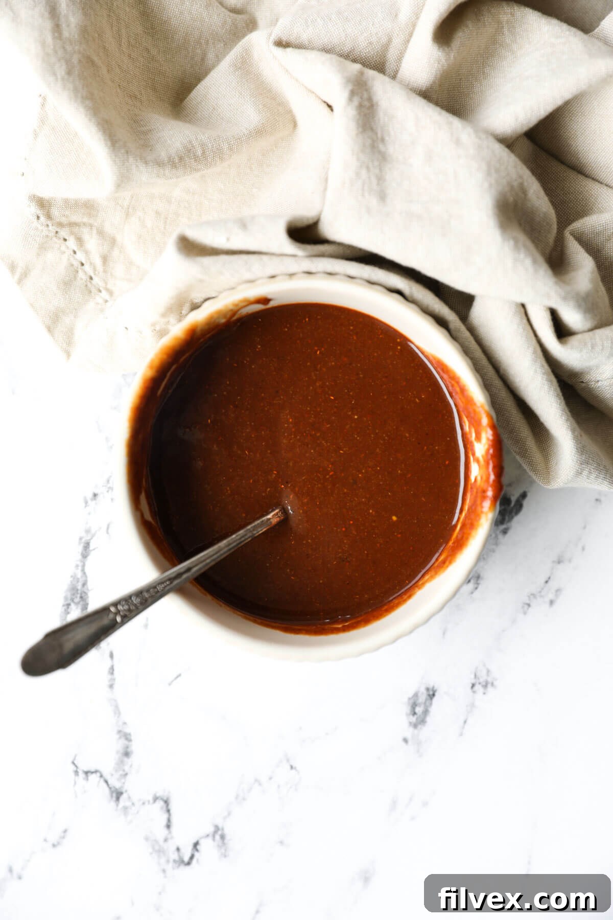 A jar of homemade Whole30 BBQ sauce next to a plate of pulled pork
