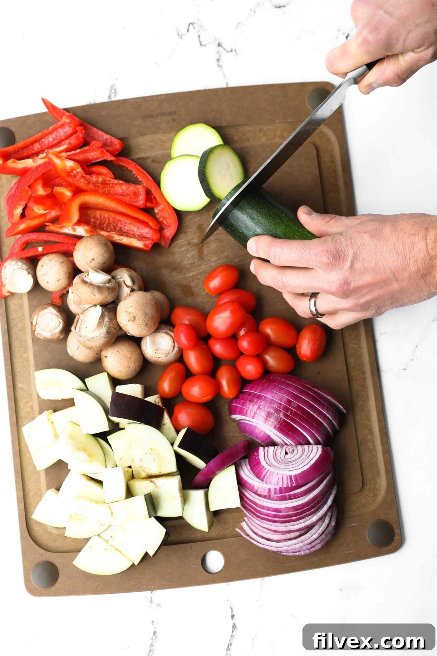 A cutting board filled with an assortment of freshly chopped vegetables, ready for grilling, including zucchini, bell peppers, onions, and mushrooms.