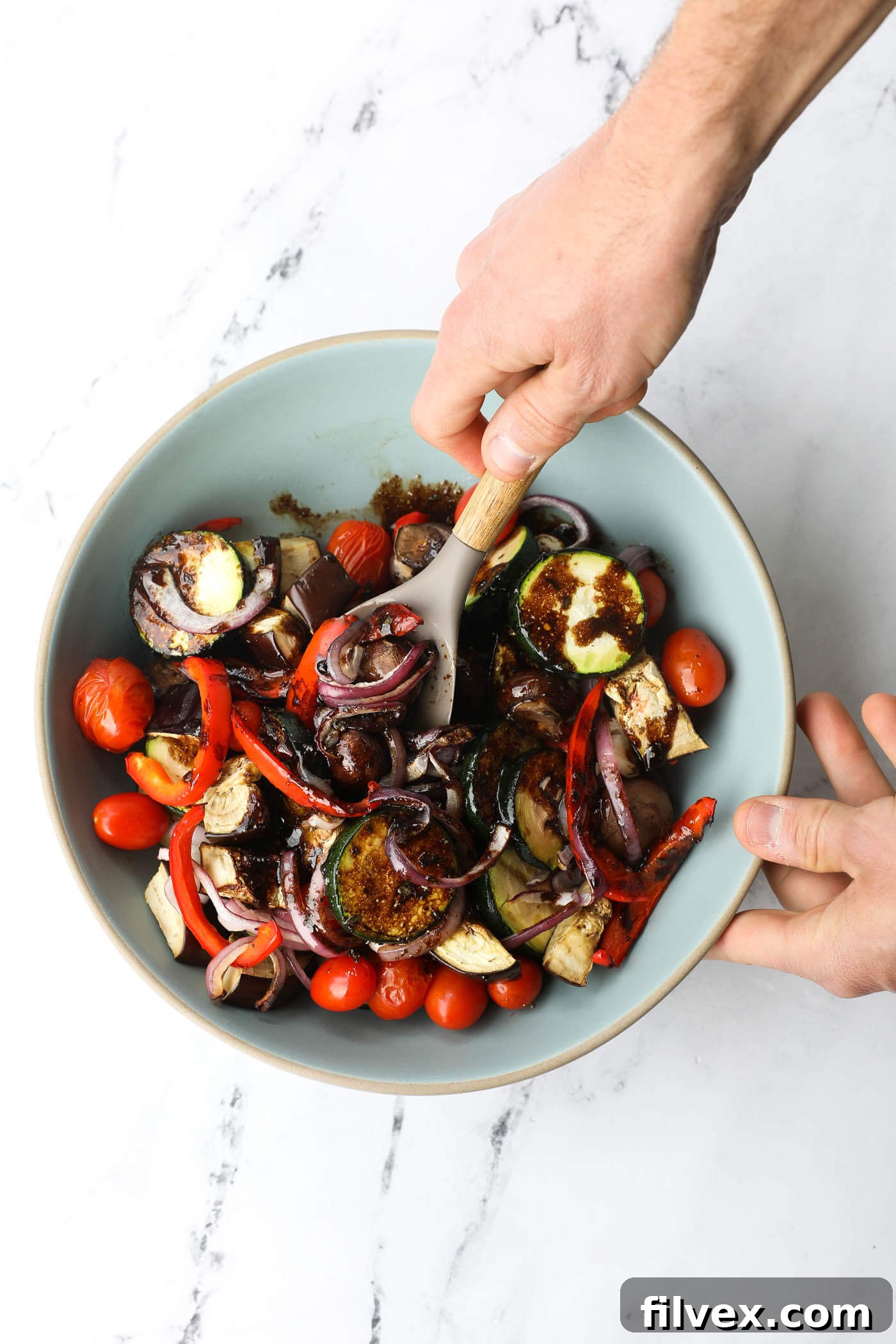 Grilled vegetables thoroughly tossed in marinade within a bowl, ready to absorb the flavors.