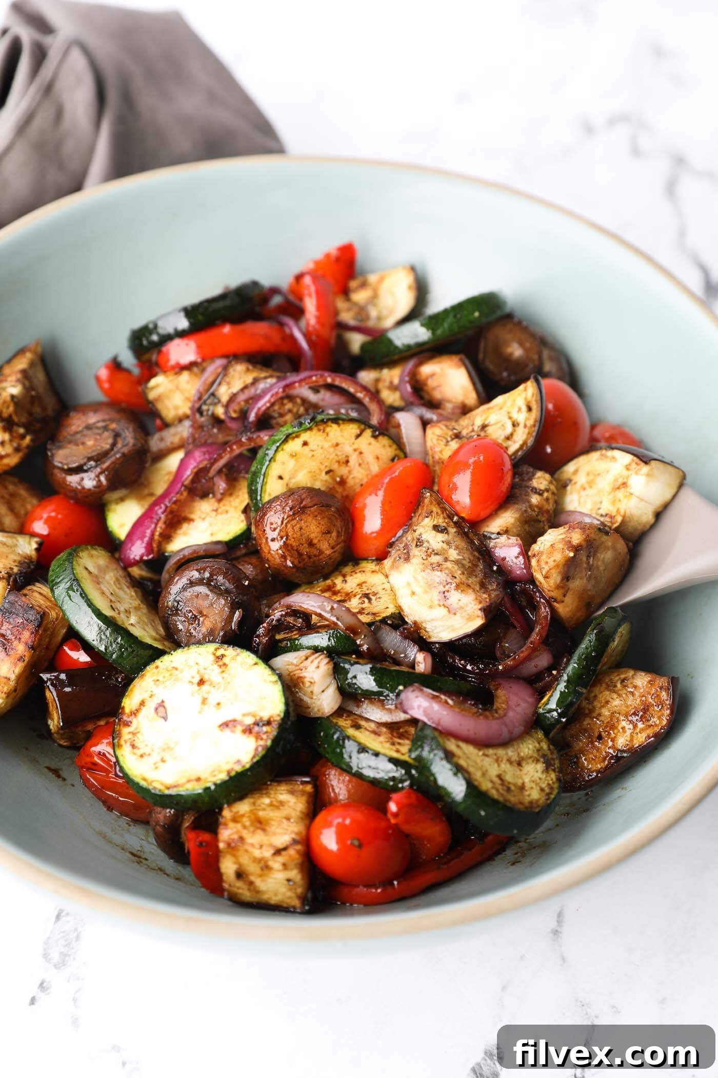 A close-up shot of grilled and marinated vegetables, emphasizing the glistening marinade and charred edges.