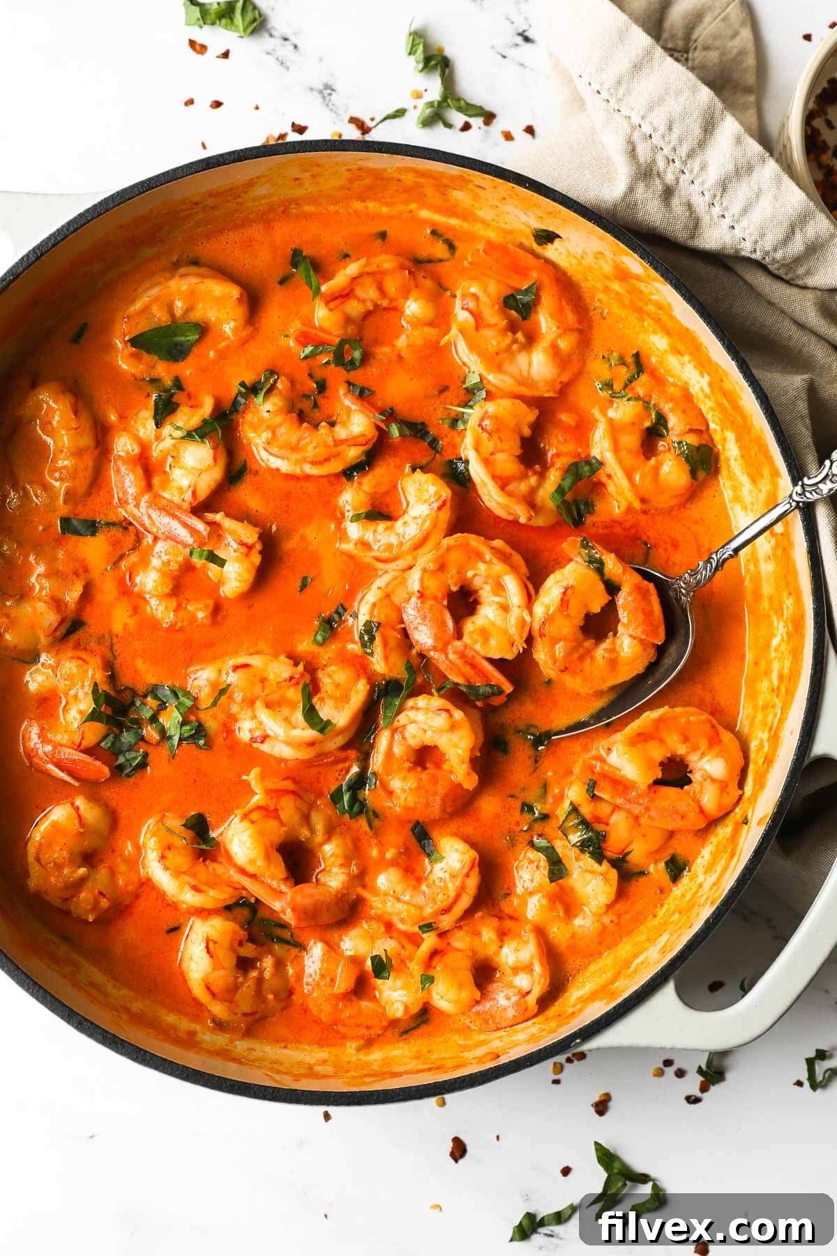 A vibrant close-up of creamy coconut shrimp in a pan, garnished with fresh herbs, ready to be served.