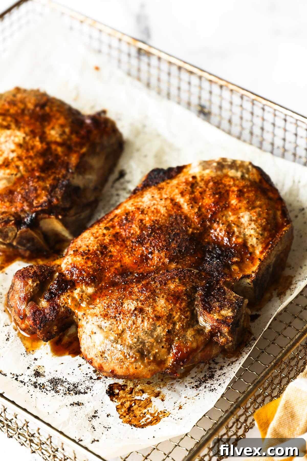A close-up of a seasoned bone-in pork chop, ready for the air fryer, showcasing the homemade spice rub.