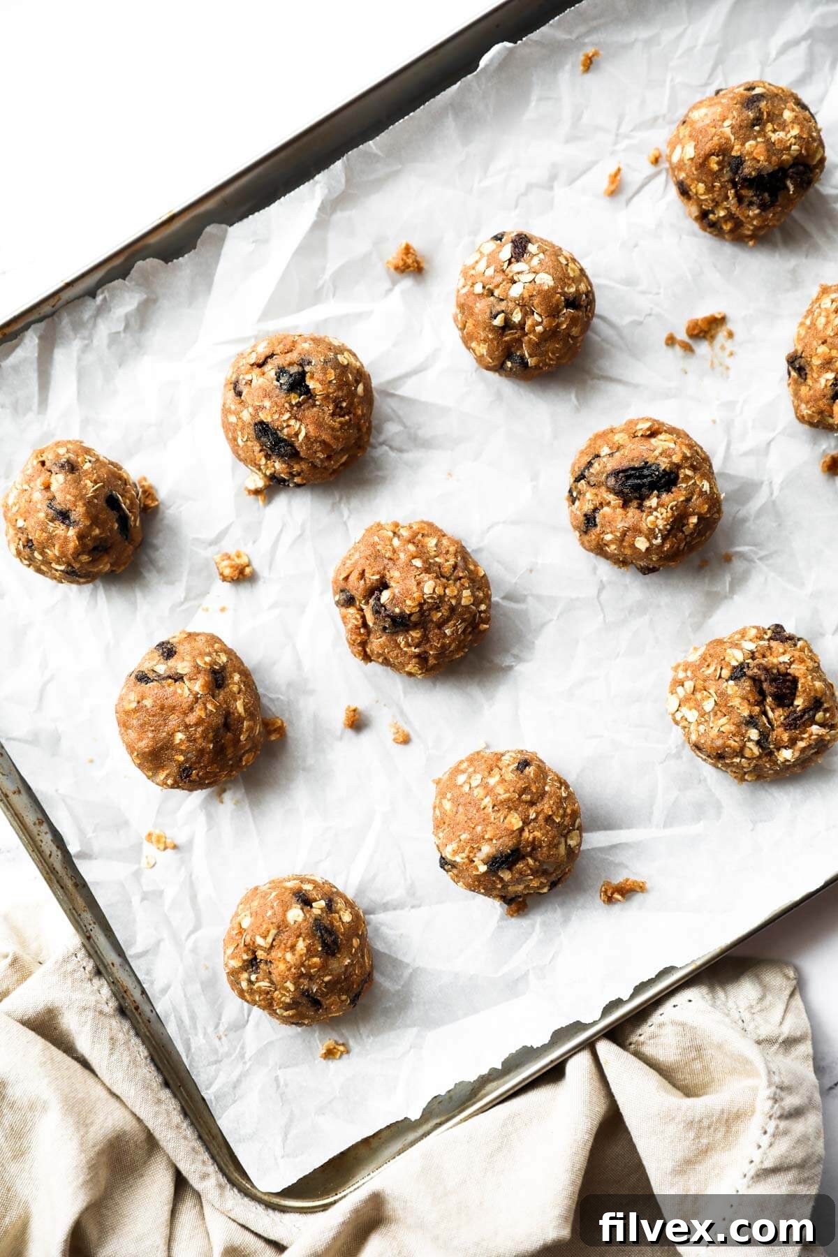 Vegan, healthy oatmeal cookies are rolled into balls and placed on a cookie sheet before baking.