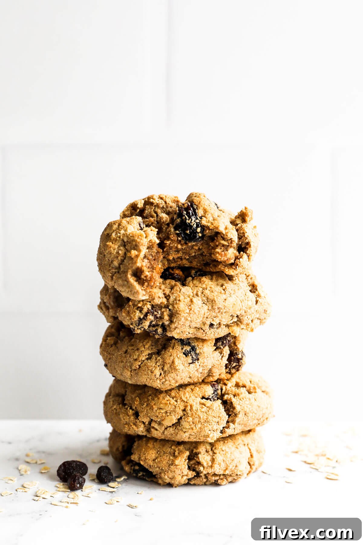 Stack of healthy oatmeal raisin cookies. The top cookie has a bite taken out of it.