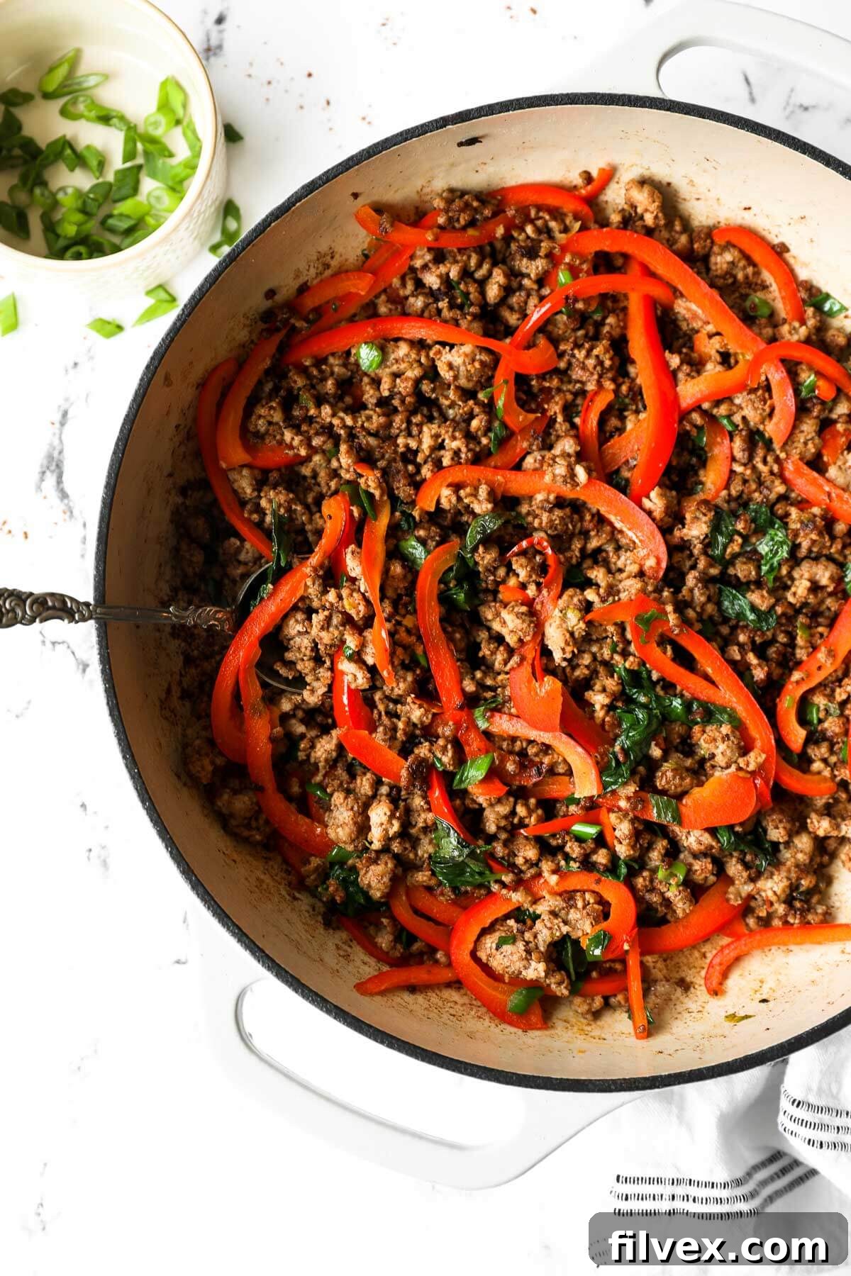 Close-up of a sizzling Thai Basil Pork stir-fry in a large wok with bell peppers and green onions, capturing the vibrant colors and textures of the dish.