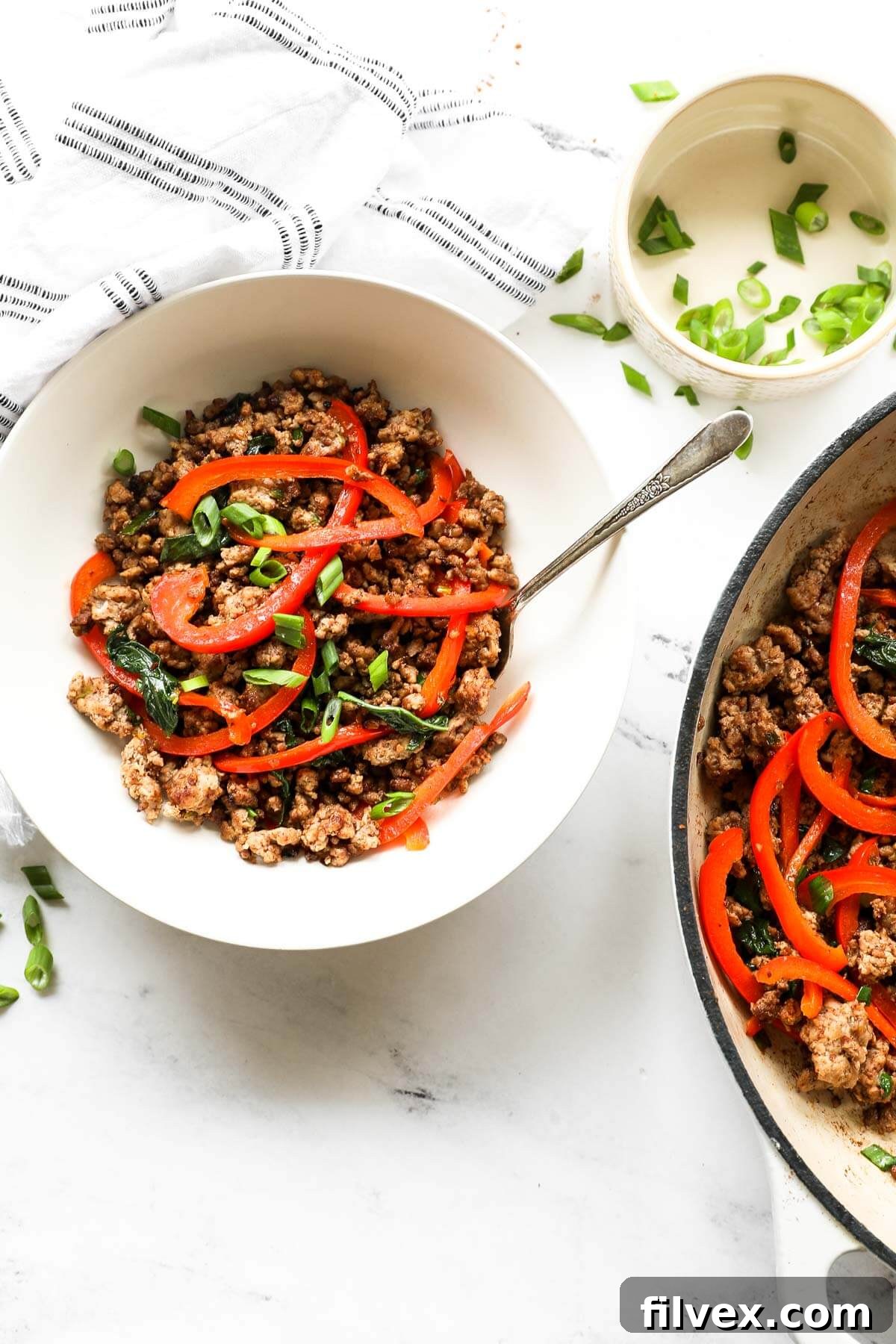 Overhead shot of prepared Thai Basil Pork served in a bowl, garnished with fresh basil leaves and red chili, highlighting its appetizing presentation.
