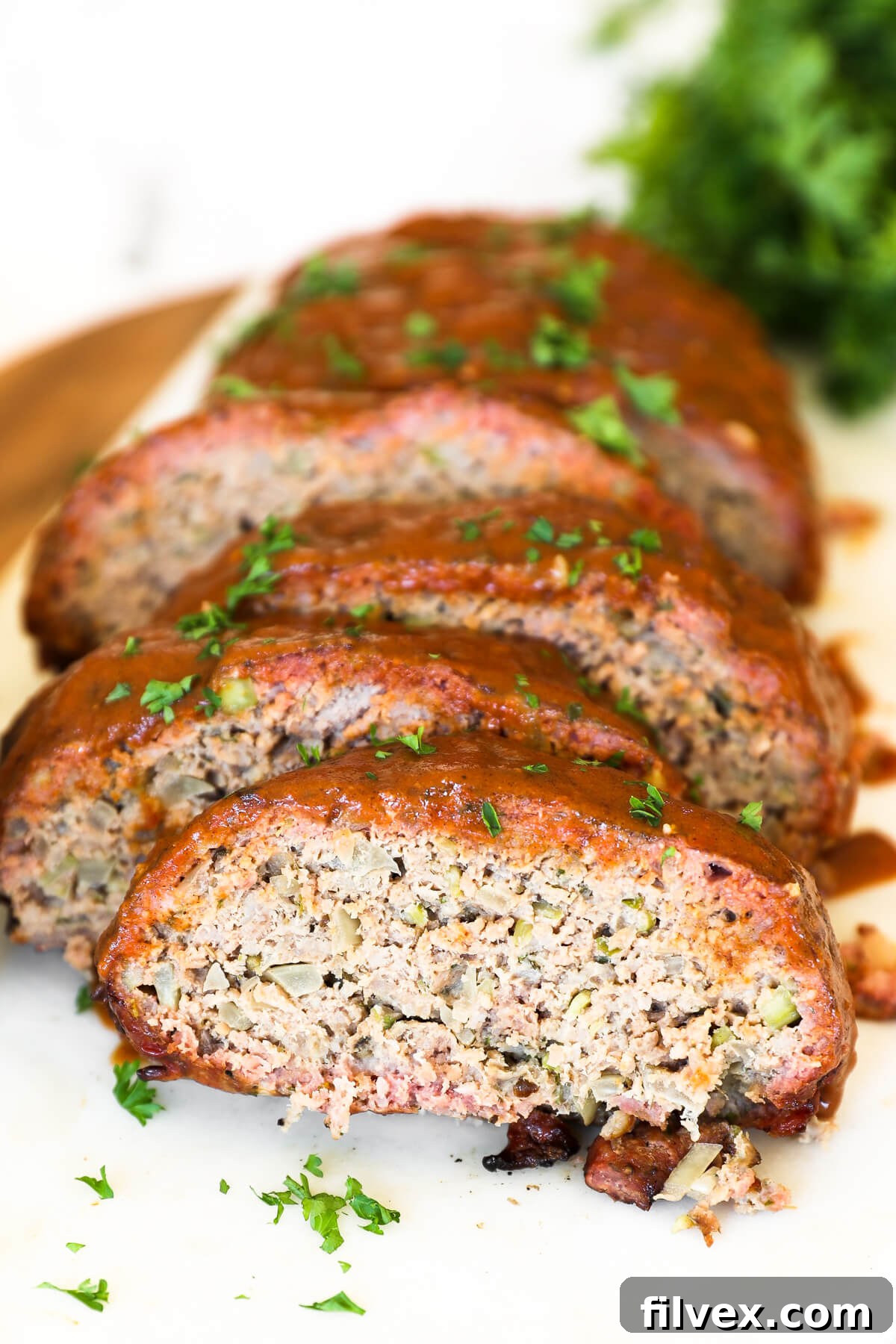 Sliced smoked meatloaf on a cutting board, garnished with fresh herbs.