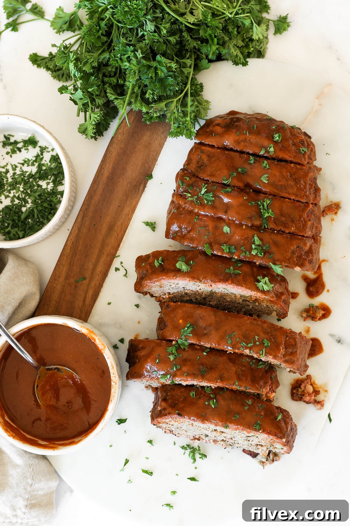 Raw meatloaf mixture being formed into a loaf shape on a baking sheet.