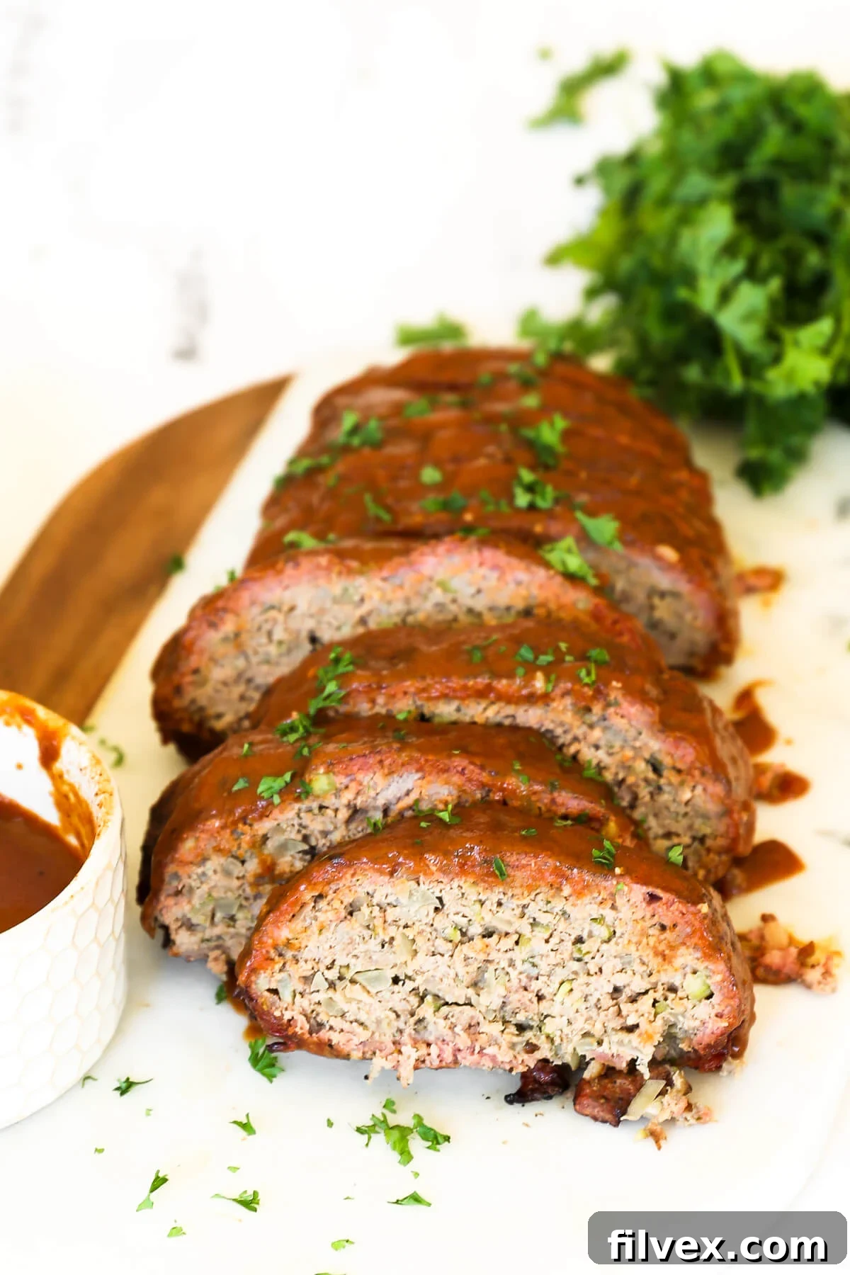 Top-down view of smoked meatloaf slices with glaze and fresh parsley.