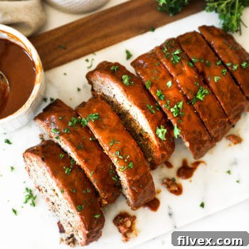 Overhead image of sliced smoked meatloaf with glaze and chopped parsley topping