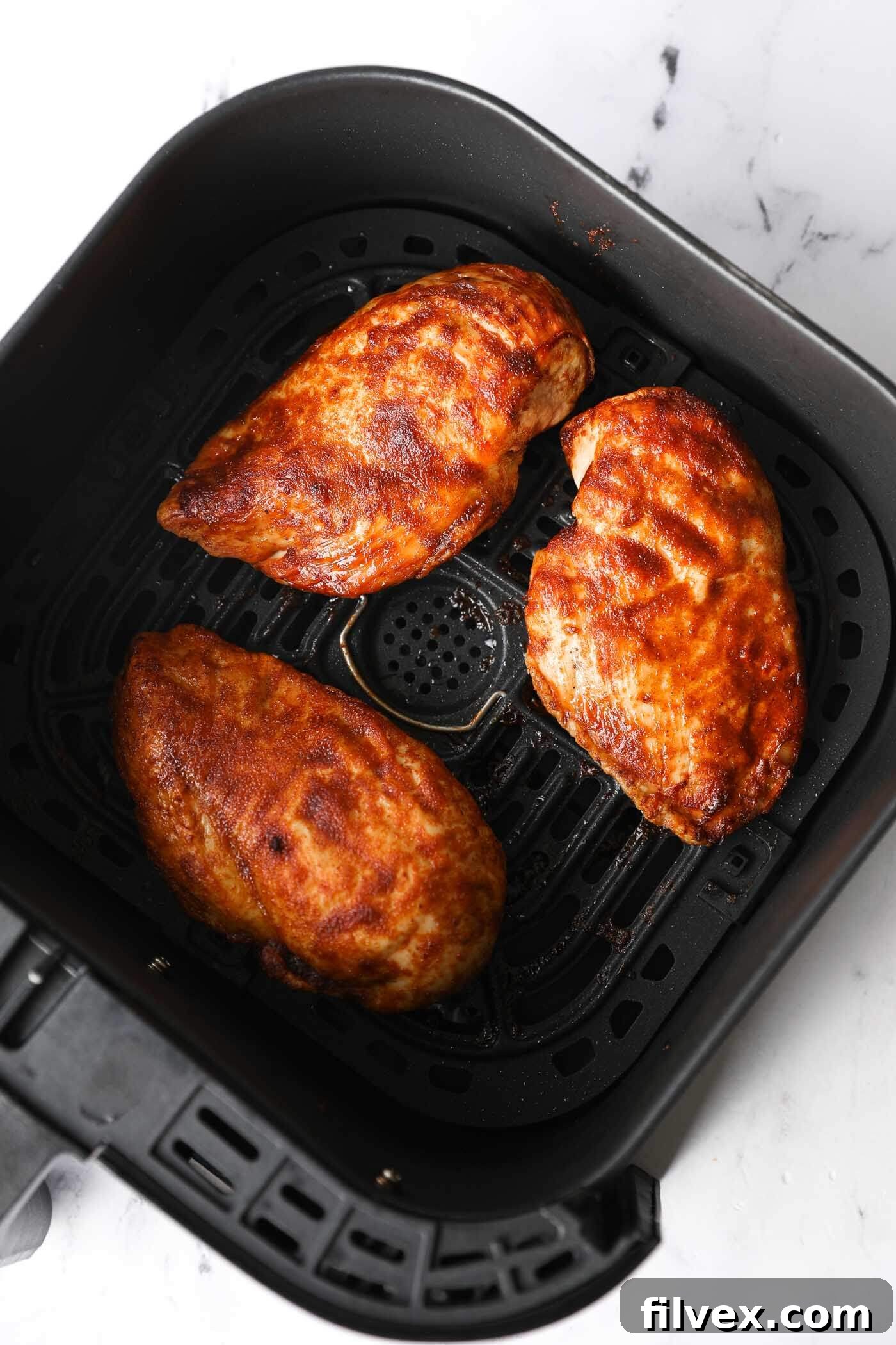Air fryer frozen chicken breast on a plate with sauce