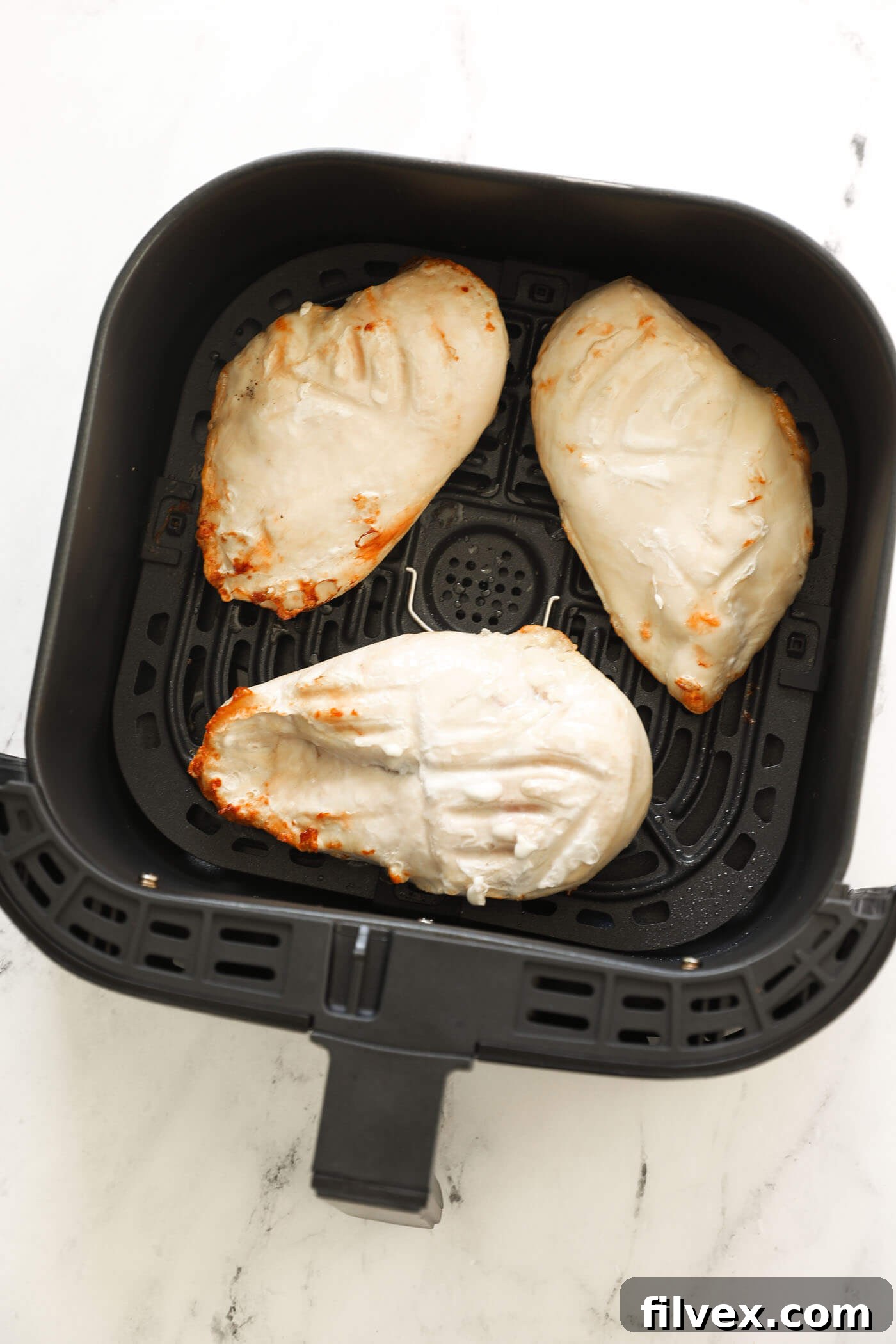 Flipping chicken breasts in the air fryer basket