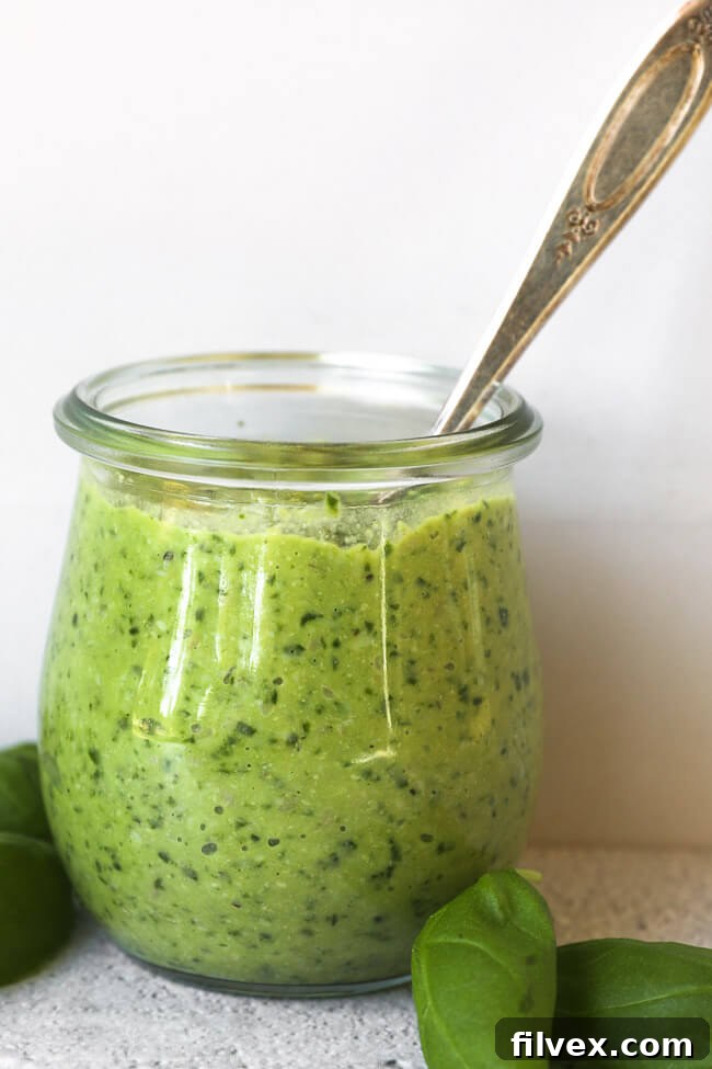 Straight-on image of a small canister filled with dairy-free and nut-free pesto, ready for serving.