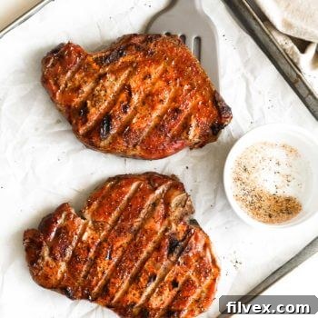 Overhead shot of traeger smoked pork chops on a pan with seasoning and spatula under one chop
