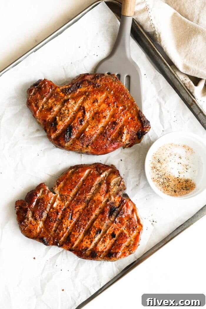 Overhead shot of two beautifully seared Traeger smoked pork chops on a metal pan, ready to be served.