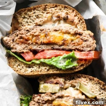 Close up overhead image of cheese stuffed keto burgers in a basket with buns, lettuce and tomato