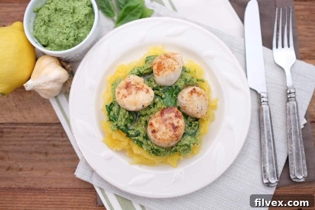 Golden-seared scallops served atop a bed of vibrant pesto spaghetti squash, garnished with fresh herbs, ready for a gourmet weeknight dinner.