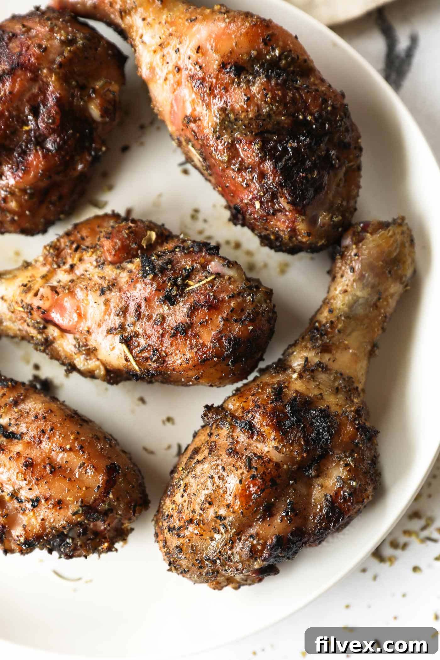 A close-up shot of seasoned raw chicken drumsticks ready for the smoker, coated evenly with a flavorful rub.