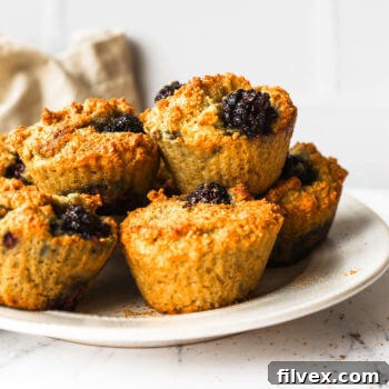 Several muffins on a plate with a couple stacked on top.