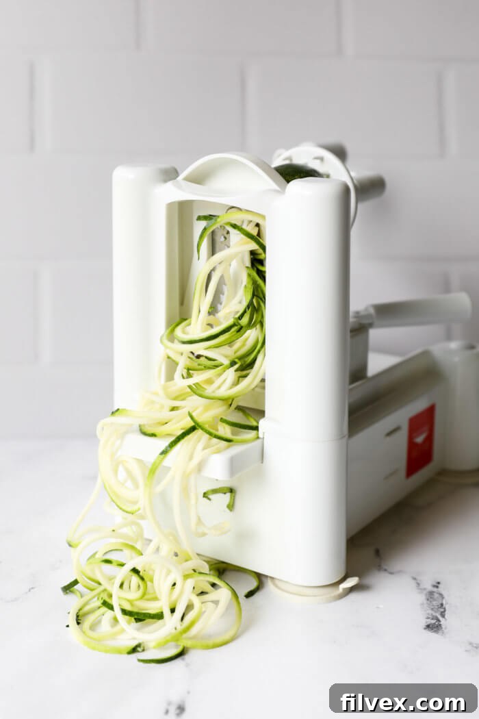 Image of zoodles coming out of a stand up spiralizer.