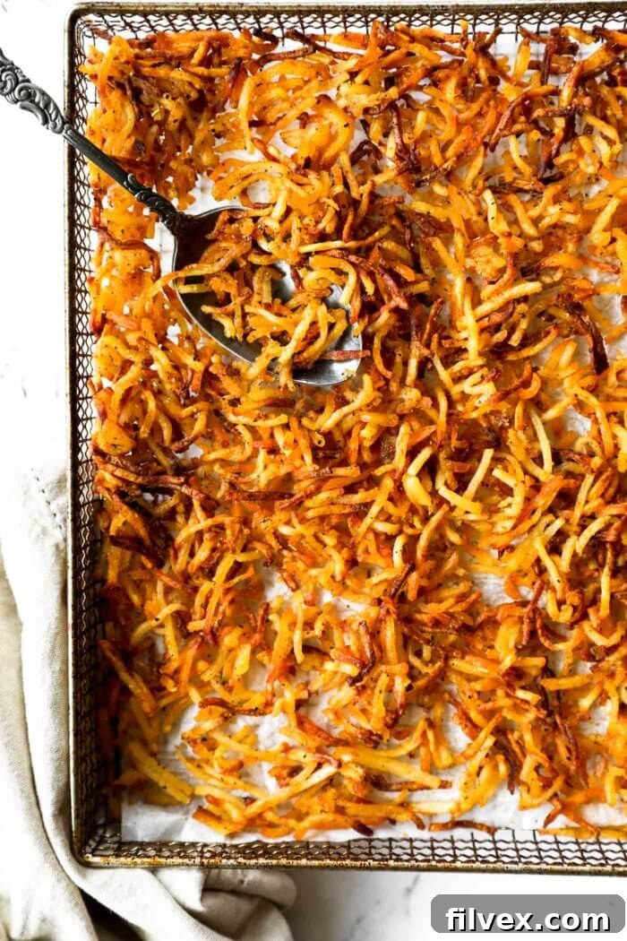 Close-up of golden-brown crispy shredded hash browns in an air fryer basket, perfectly cooked