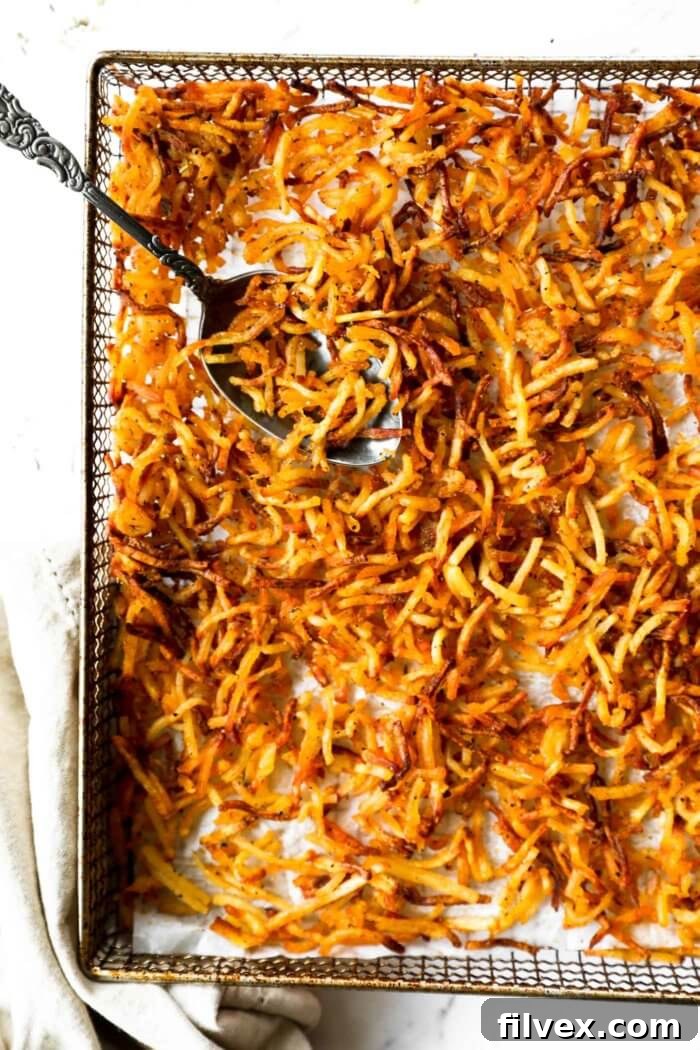 Overhead shot of crispy air fryer hash browns on a white plate with a fork, ready to eat