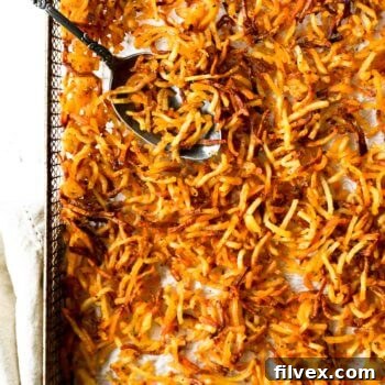Close up overhead of air fryer hash browns in a basket with spoon