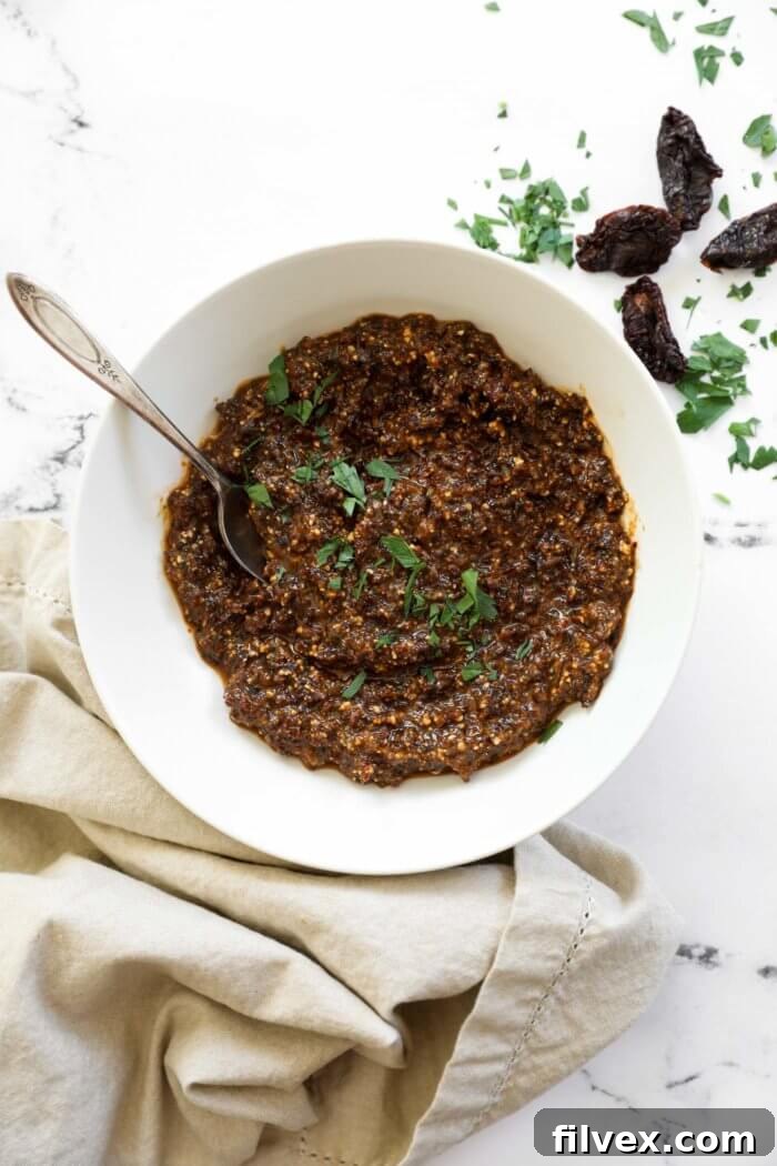 Close-up of a spoon scooping sun-dried tomato pesto from a bowl