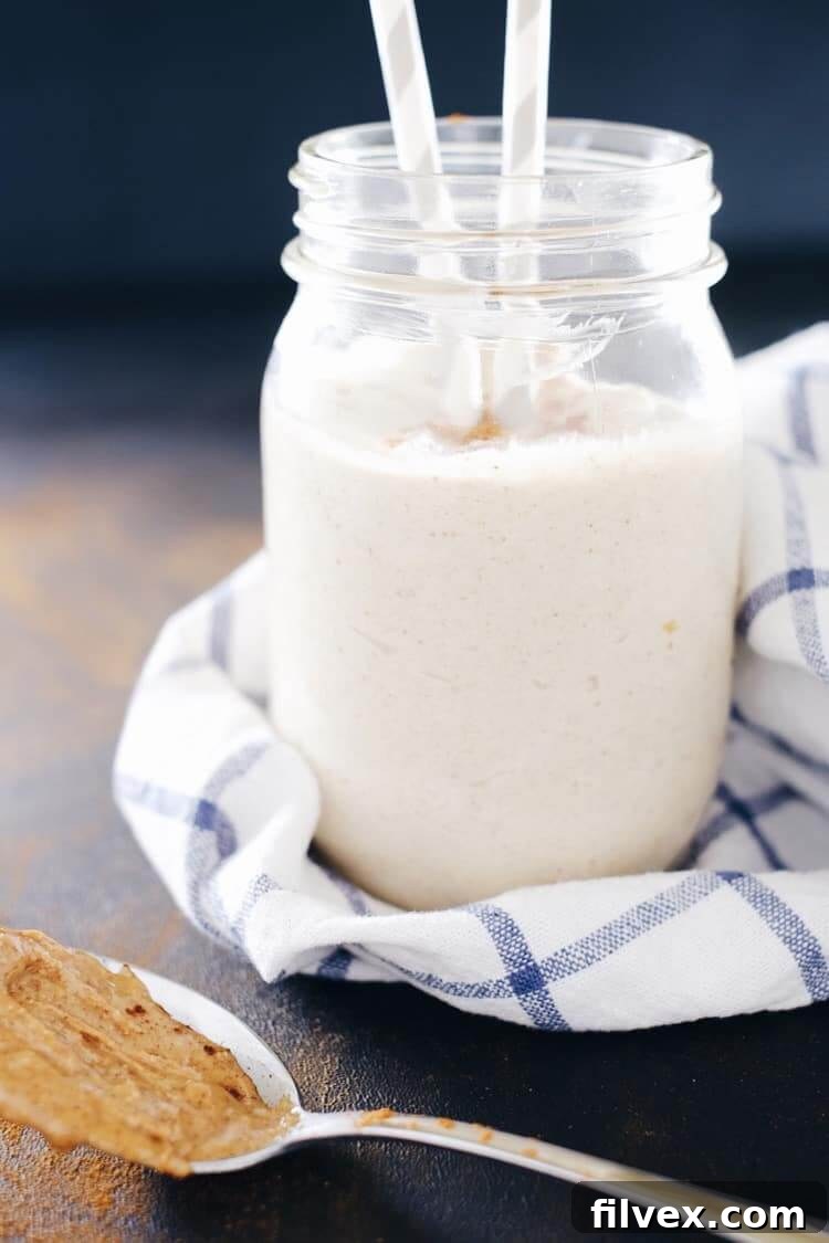 A top-down view of a banana almond butter smoothie in a glass, with a spoon resting in it, highlighting its rich, creamy texture and a sprinkle of cinnamon on top. Ideal for a healthy, quick, and satisfying meal.