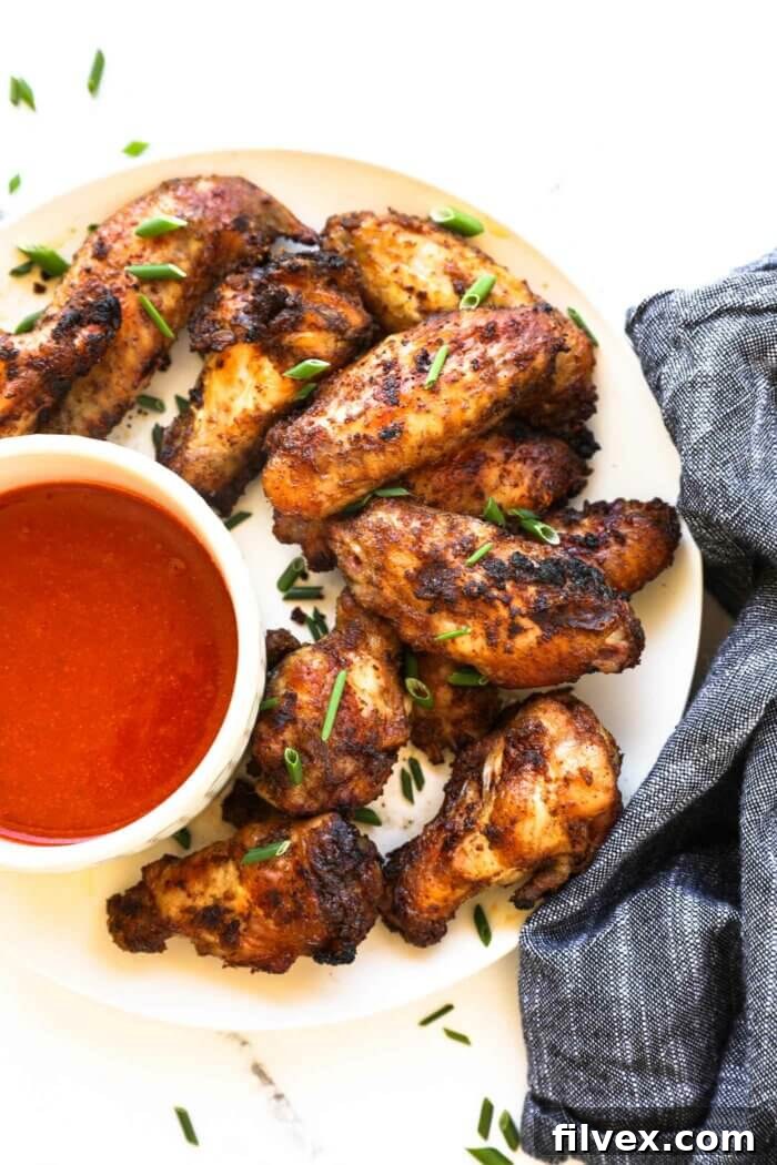 Close up overhead image of crispy wings on a plate with a side of buffalo sauce.