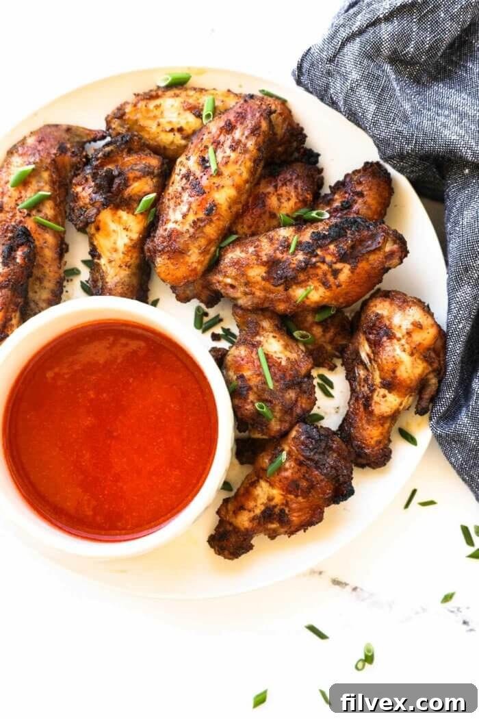 Overhead image of a plate with crispy chicken wings and a ramekin of buffalo sauce.