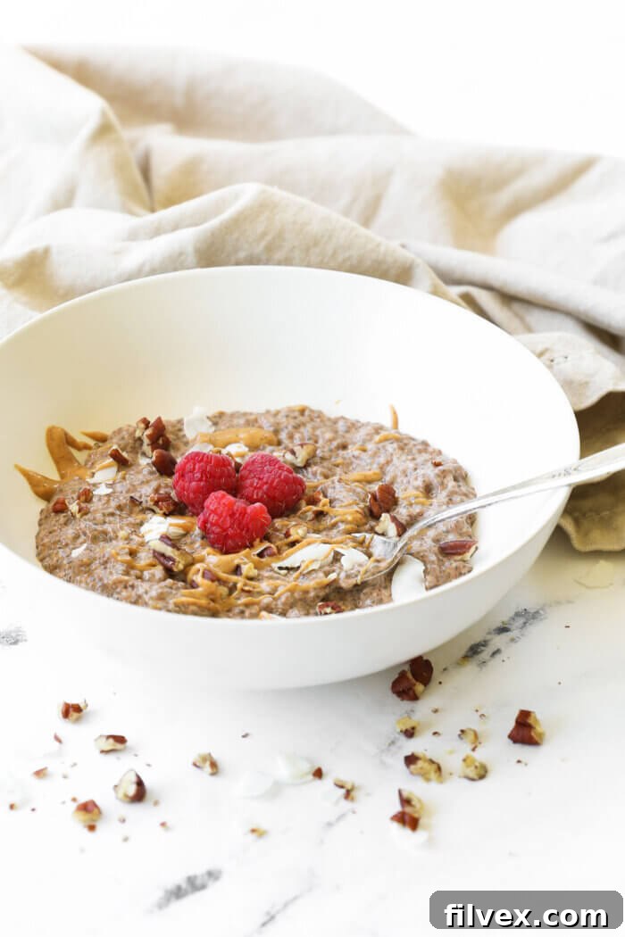 Angled view of a bowl of creamy keto chia pudding with a spoon dipped in, showcasing its delightful texture and readiness to be enjoyed.