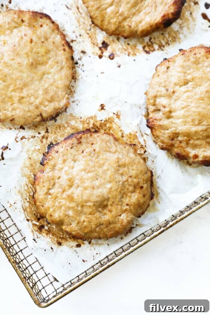 A close-up shot of a perfectly cooked, golden-brown turkey burger patty resting in the basket of an air fryer, highlighting its juicy texture.