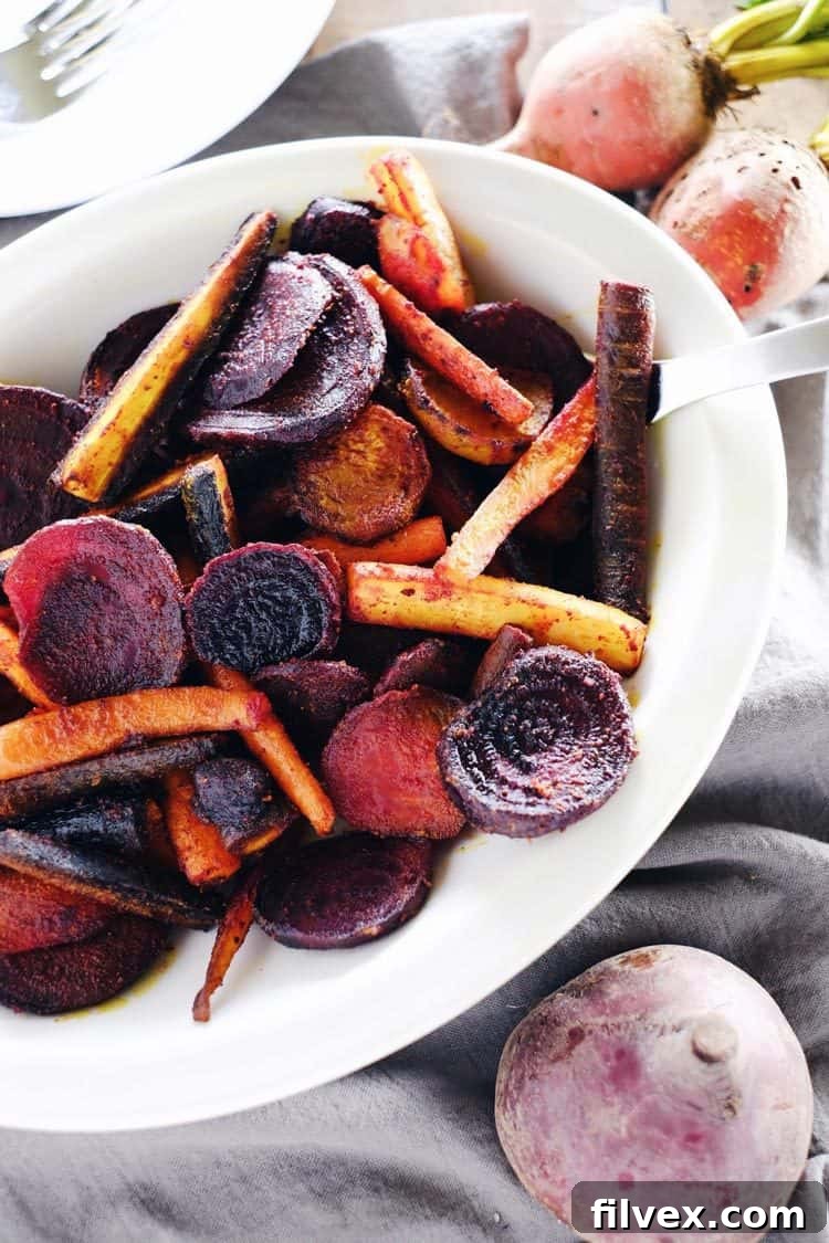 A close-up of beautifully roasted beets and carrots, seasoned with turmeric and maple, perfect for a healthy diet.