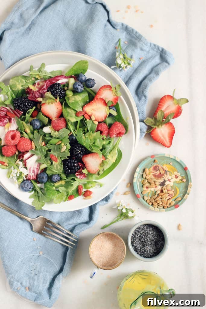 Refreshing Berry Bliss Salad with a spicy mango poppy seed vinaigrette, perfect for summer.