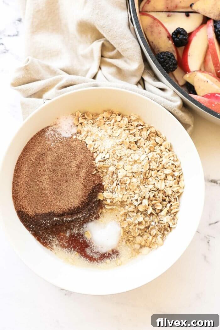 Overhead image of a bowl full of crumble ingredients before being mixed up, showcasing almond flour, oats, coconut sugar, and other dry ingredients.