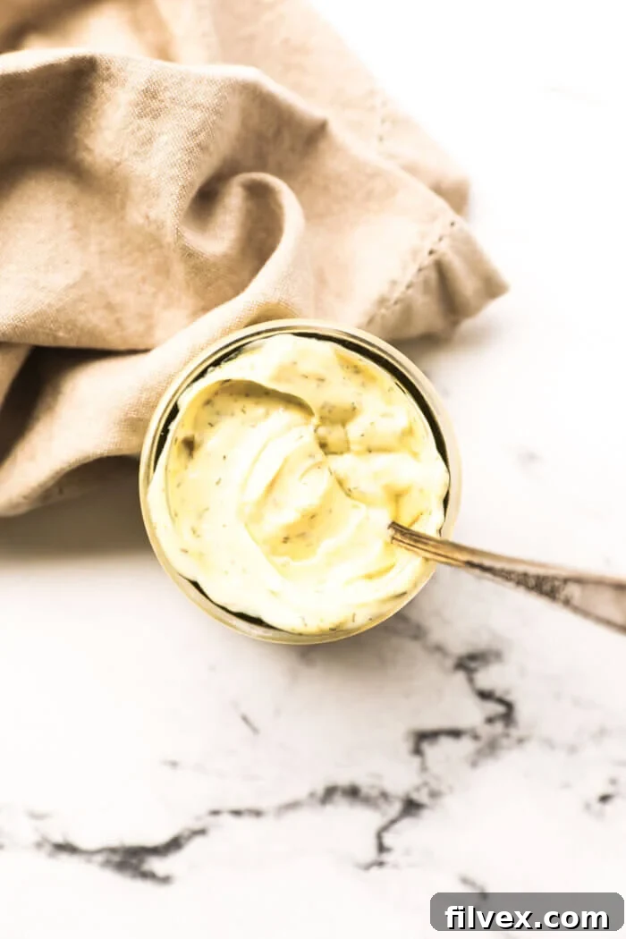 Overhead image of a jar of tartar sauce with a spoon dug in, showcasing its creamy texture.