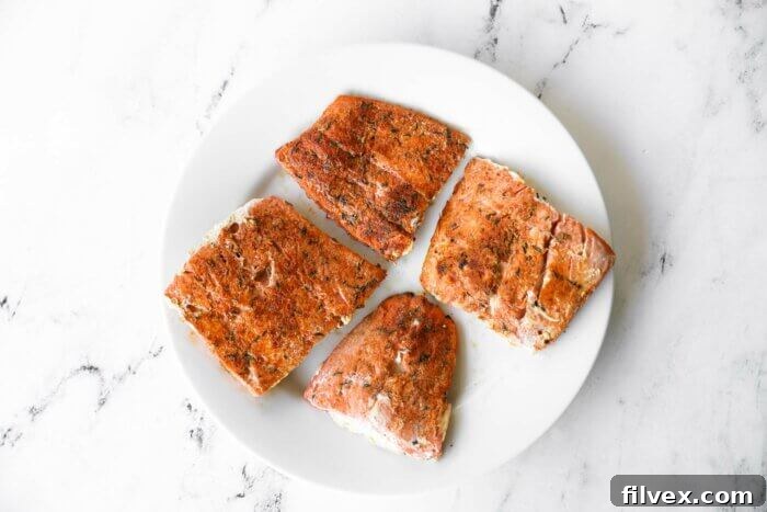 Four cooked salmon filets on a plate.