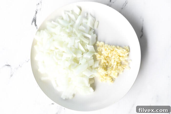 Diced onion and minced garlic on a plate.