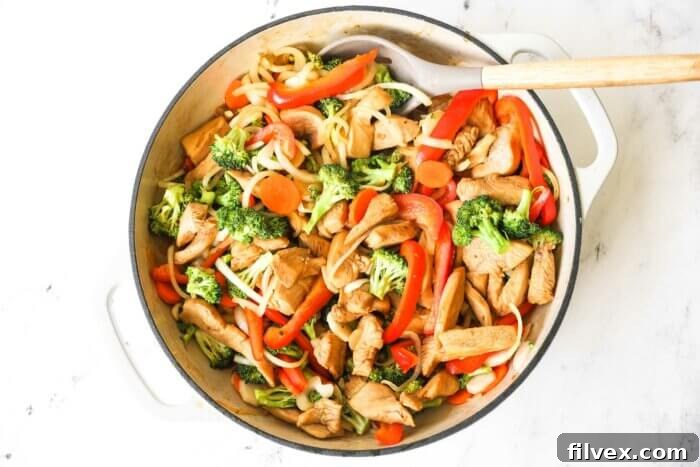 Cooked marinated chicken stir fry in a skillet with spoon