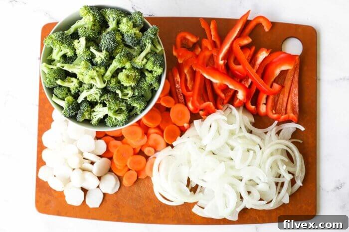 Chopped broccoli, water chestnuts, carrots, onion and red bell pepper on a board