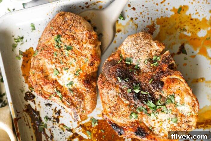 Cooked oven baked bone in pork chops resting on a sheet pan