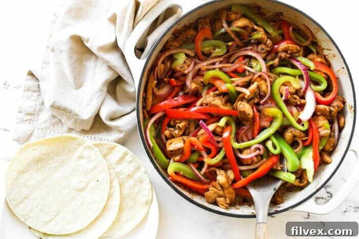 Finished sizzling skillet chicken fajita tacos in a skillet with tortillas on the side