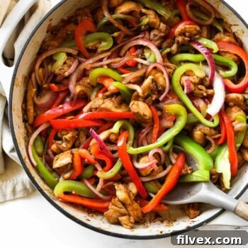 Overhead image of chicken fajita tacos fillings in a skillet with spoon
