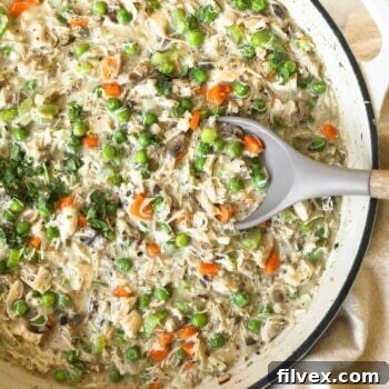 Overhead image of a single serving of crustless chicken pot pie with peas, carrots, and mushrooms, garnished with fresh parsley.