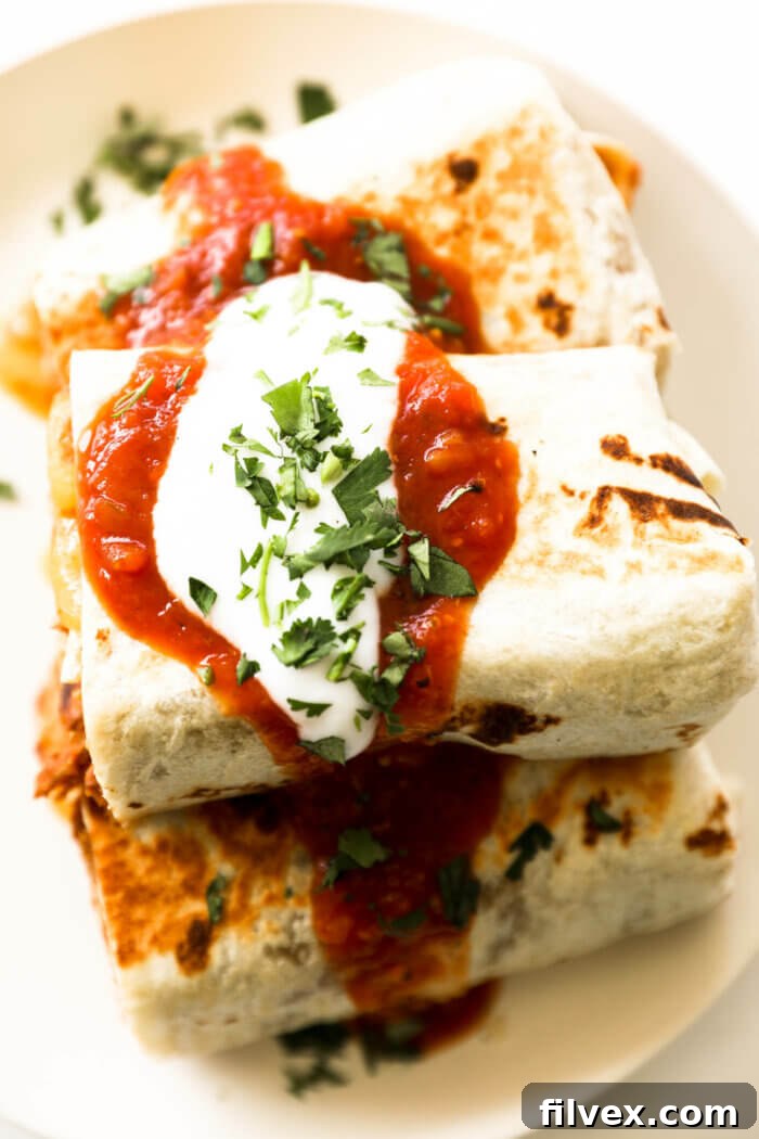 Close-up of a half-eaten carnitas burrito showing the layers of filling inside.